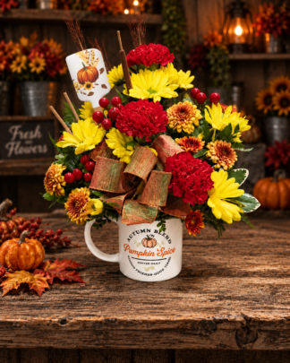 Pumpkin Spice fall flower arrangement with red, yellow and bronze autumn blooms, berries, wheat and a pumpkin spatula in a keepsake mug.