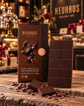 Neuhaus Dark Chocolate from Ecuador with cacao nibs, displayed with dark chocolate pieces on a rustic wood table in an elegant Belgian chocolate shop setting.