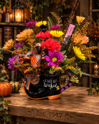 Boot Scootin’ Broomie Halloween flower arrangement in a whimsical witch boot keepsake with colorful fresh flowers and festive accents.